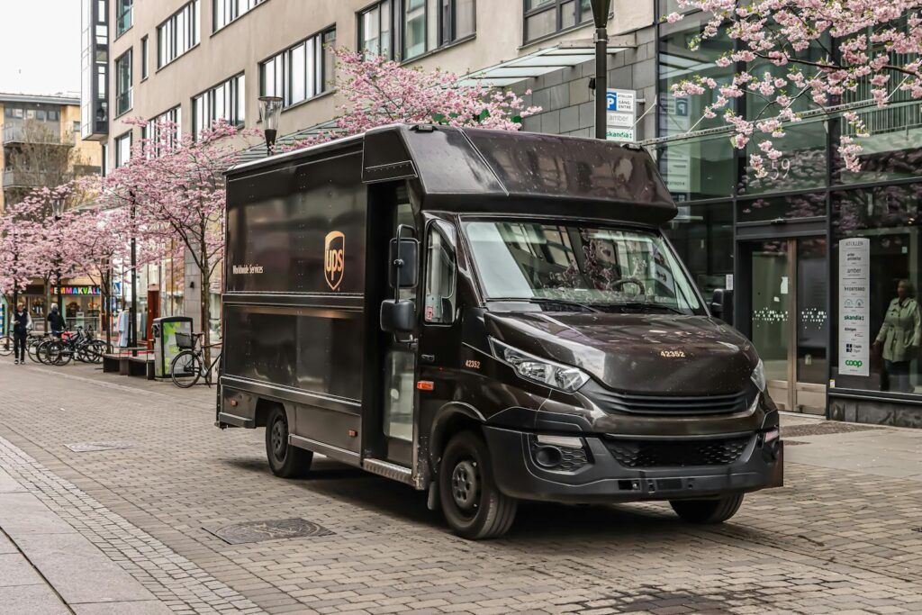 Black UPS delivery truck parked on a street in Jönköping, Sweden with cherry blossoms in spring.