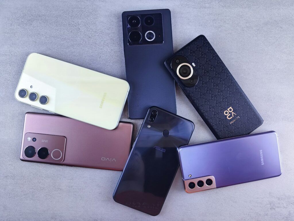 Several smartphones from different brands lying on a grey surface