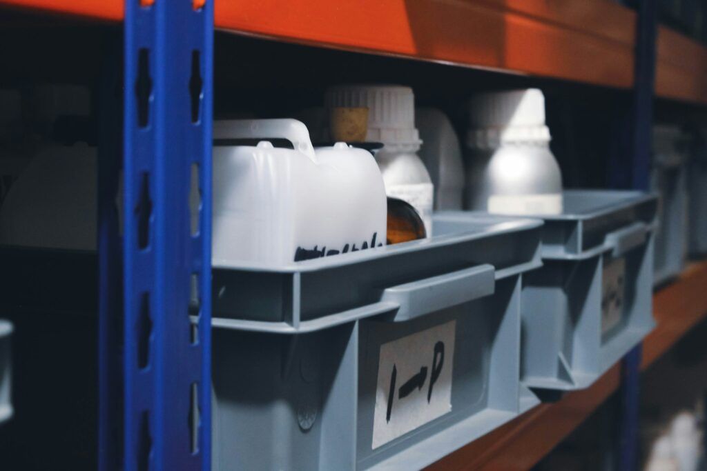 Grey plastic bins with location labels on blue and orange warehouse racking