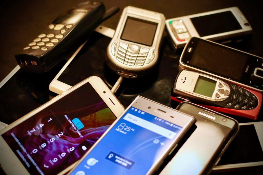 Pile of old and new mobile phones of different brands and colours