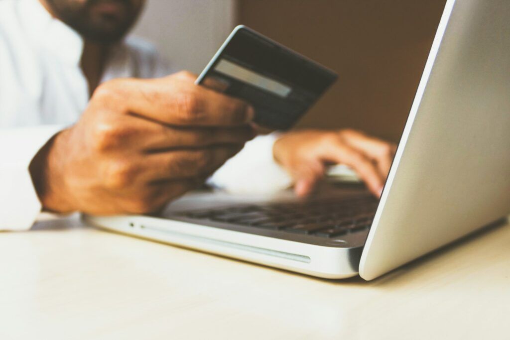 Person holding a bank card while shopping online on a laptop
