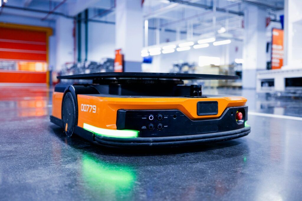 Orange autonomous mobile robot driving across a warehouse floor